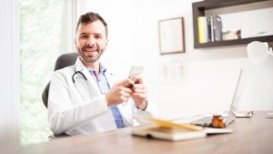 Médico em consultório usando o celular para usar o Instagram