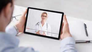 Homem assistindo a um vídeo médico de uma doutora em um tablet