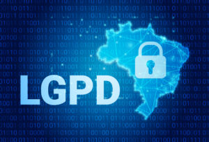 Como a Dra. Denise Branco segue a LGPD com o Afya iClinic? 1 Sigla LGPD ao lado do mapa do Brasil com cadeado no meio, com código binário ao fundo azul