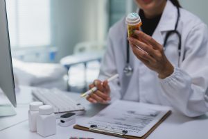 Médico segurando frasco de medicamento enquanto revisa informações de prescrição 