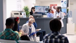 Recepção de uma clínica médica lotada de pacientes sentados em cadeiras
