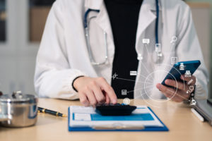 Aprenda a fazer o imposto de renda para médicos sem erros! 1 Médico usando uma calculadora para saber quanto de imposto de renda irá pagar