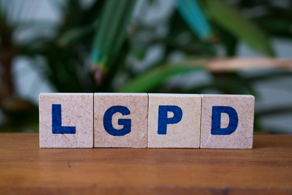 Dados com letras formando a sigla LGPD em cima de uma mesa