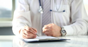 Médico preenchendo histórico do paciente, essencial para o marketing digital da clínica