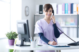 Recepcionista de uma clínica médica atendendo um telefone