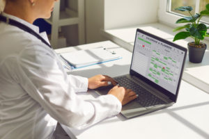 Médico em frente a um computador estudando aspectos administrativos da clínica
