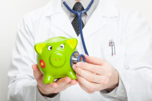Médico segurando um cofre de porquinho verde em uma mão e na outra um estetoscópio