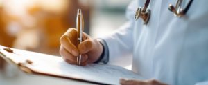 Médico fazendo anotações de protocolos clínicos em uma prancheta 