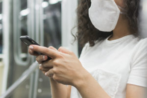 Mulher com máscara utilizando celular