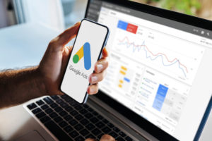 Médico segurando um celular na frente da tela do computador com o Google Ads aberto
