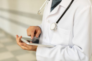Médico utilizando tablet com tela sensível ao toque, simbolizando a digitalização de prescrições e documentos médicos