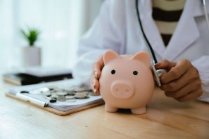 Médico examinando cofrinho com estetoscópio, simbolizando economia e gestão financeira na saúde