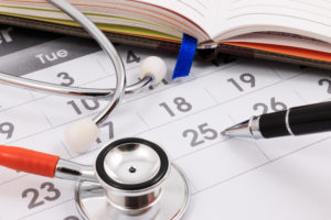 Calendário com caneta, estetoscópio e agenda em cima