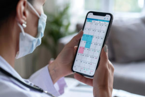 Médica conferindo a agenda de pacientes em um smartphone