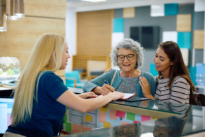 Recepcionista atendendo duas pacientes em clínica médica