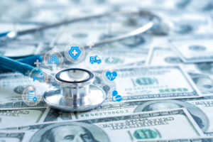 Dólares embaixo de um estetoscópio com ícones de gestão financeira médica em volta