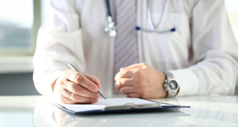 Médico preenchendo histórico do paciente, essencial para o marketing digital da clínica