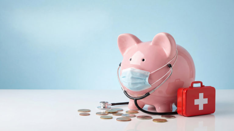 Cofre porquinho rosa usando um estetoscópio e uma maleta vermelha ao lado de muitas moedas