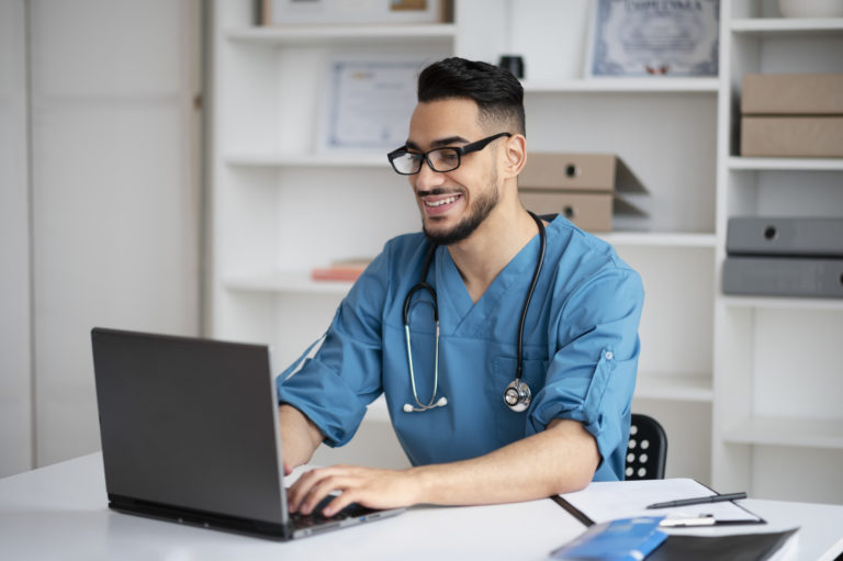 Médico trabalhando em consultório utilizando computador